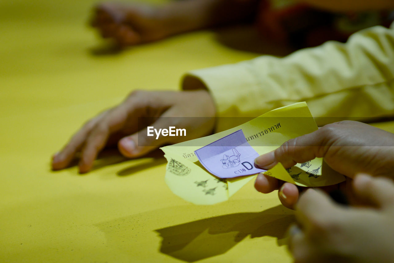 Cropped hand of person holding paper on table