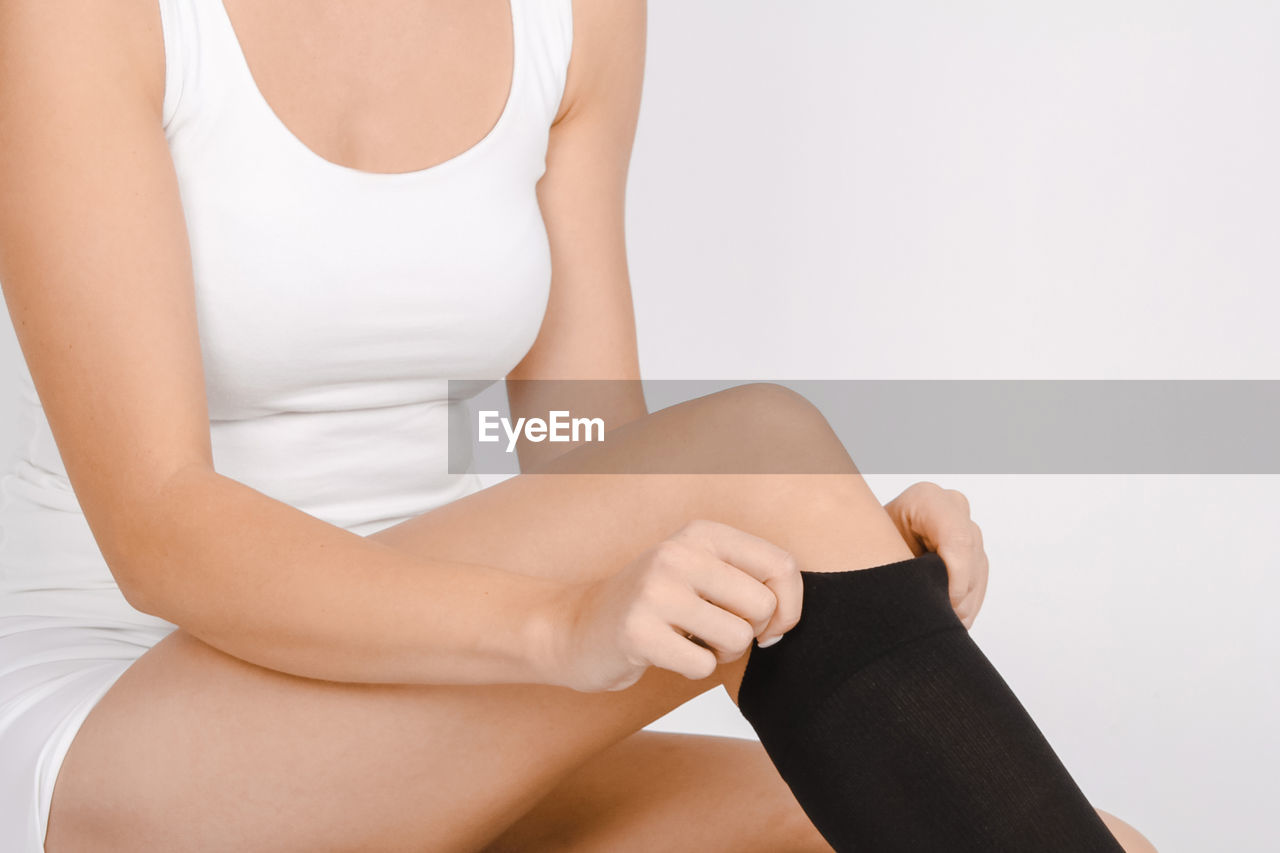 Midsection of woman wearing stockings against white background