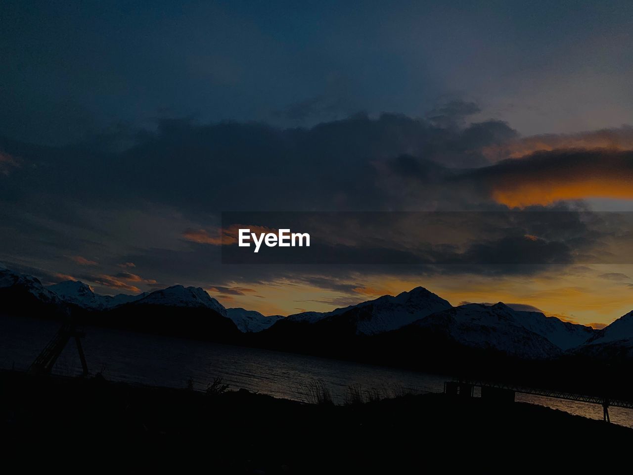 SCENIC VIEW OF LAKE BY SILHOUETTE MOUNTAINS AGAINST SKY DURING SUNSET