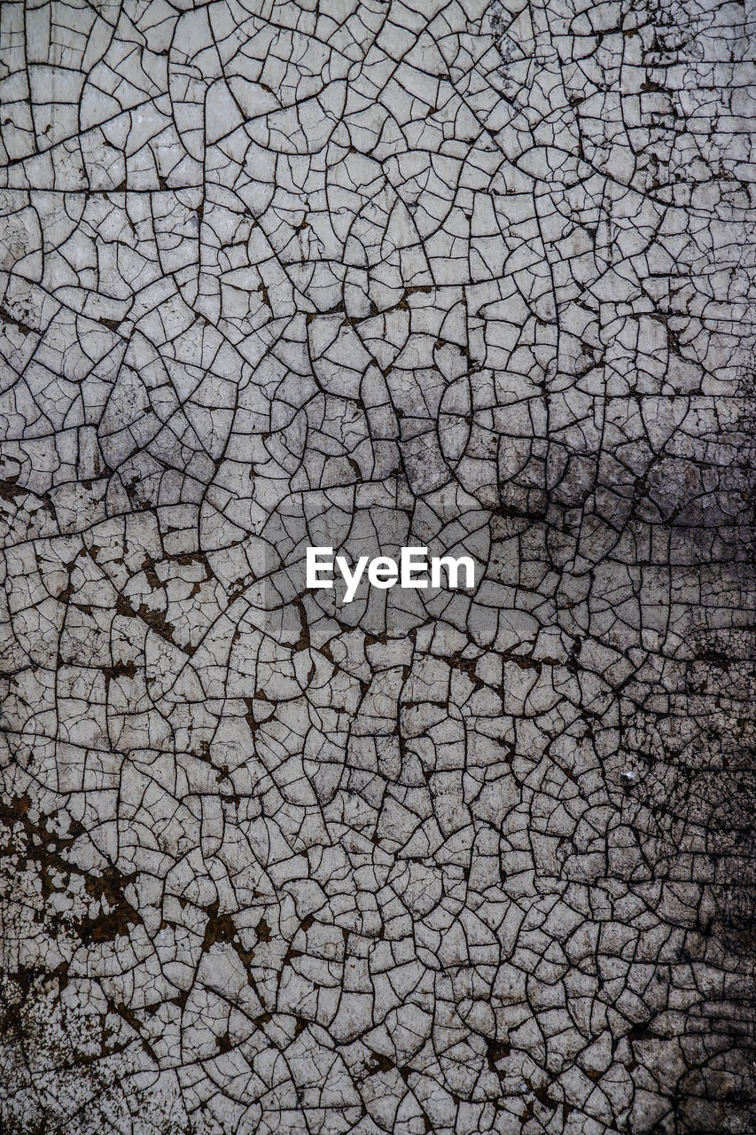 FULL FRAME SHOT OF CRACKED LAND ON DRY LEAVES