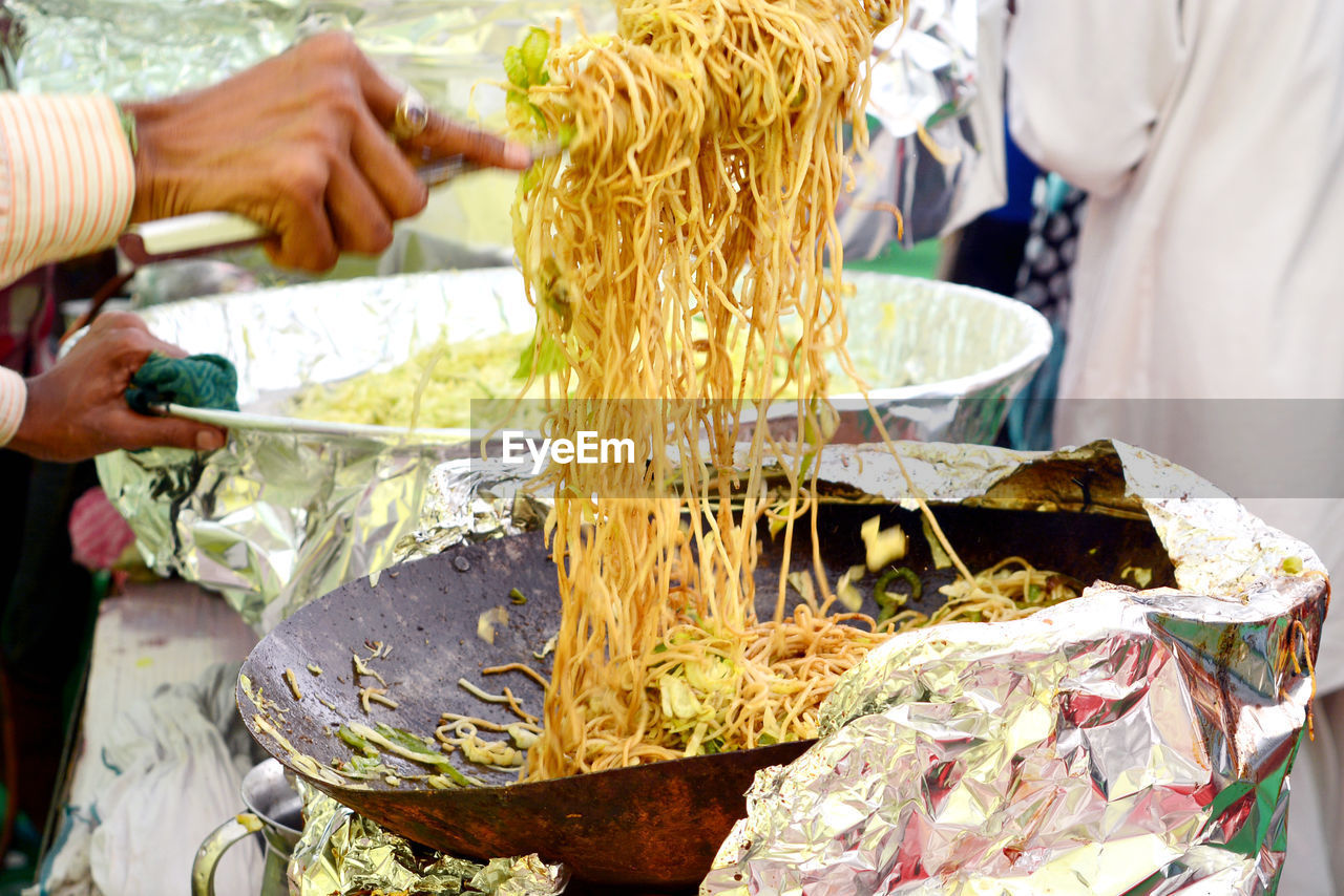 CLOSE-UP OF PERSON PREPARING FOOD AT MARKET