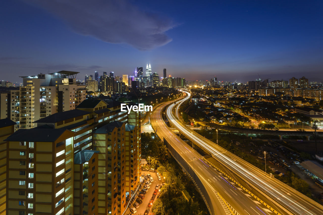 HIGH ANGLE VIEW OF ILLUMINATED CITY BUILDINGS AT NIGHT