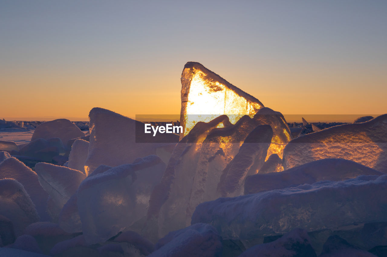 low angle view of man standing on rock against sky during sunset