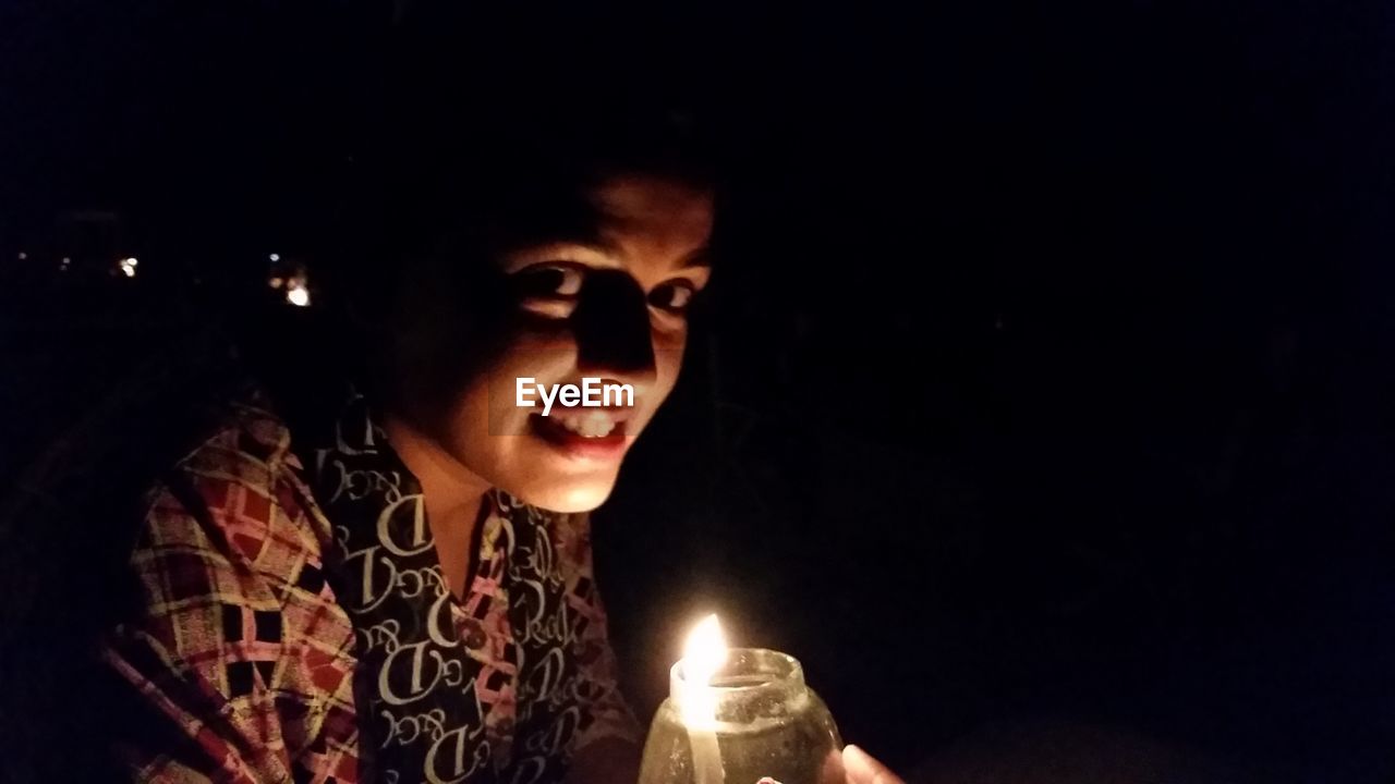 Close-up portrait of woman by candle at night