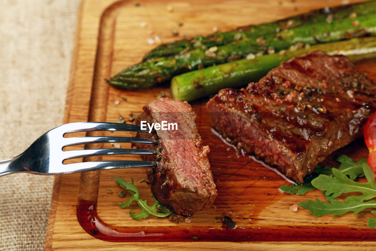 Close-up of grilled meat and asparagus on cutting board