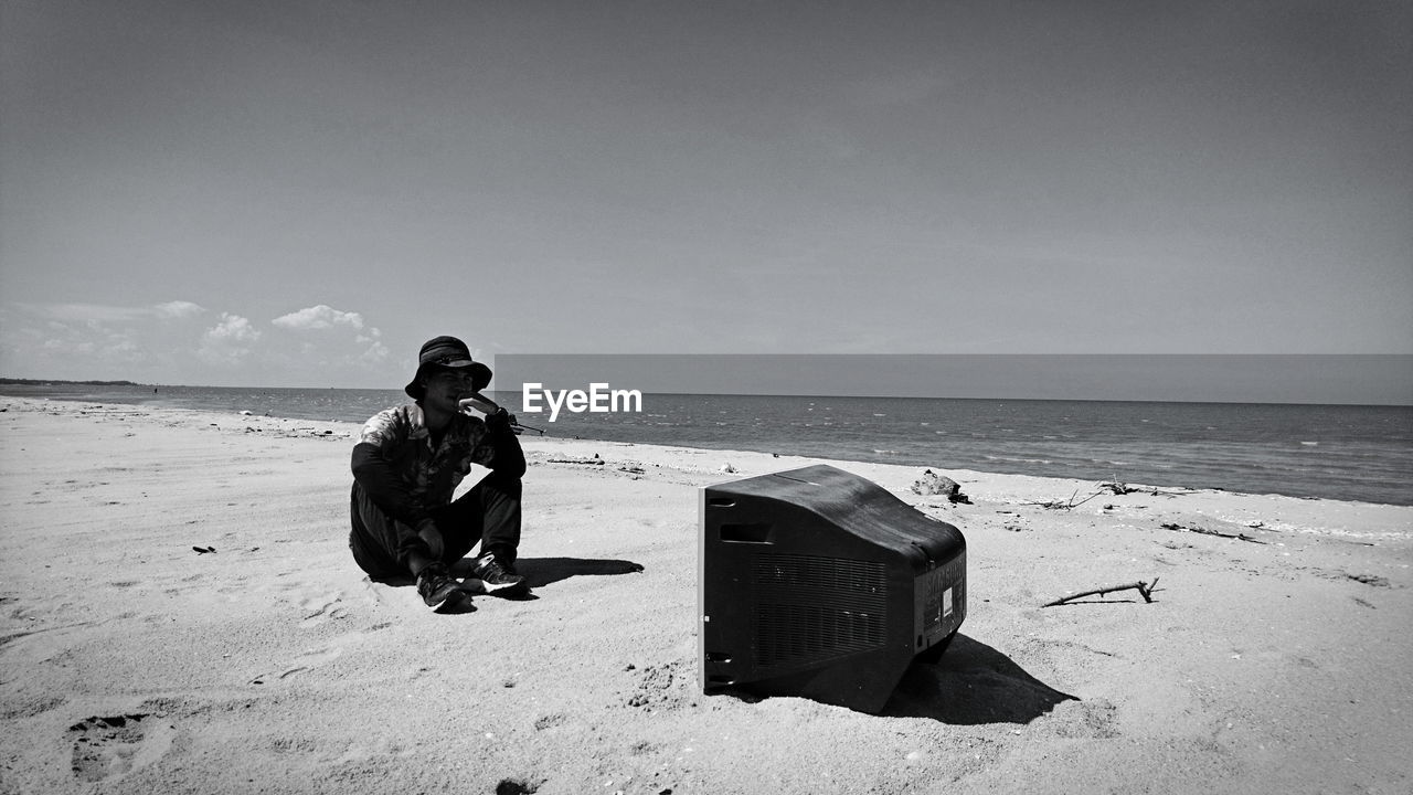 Man sitting by television set at beach