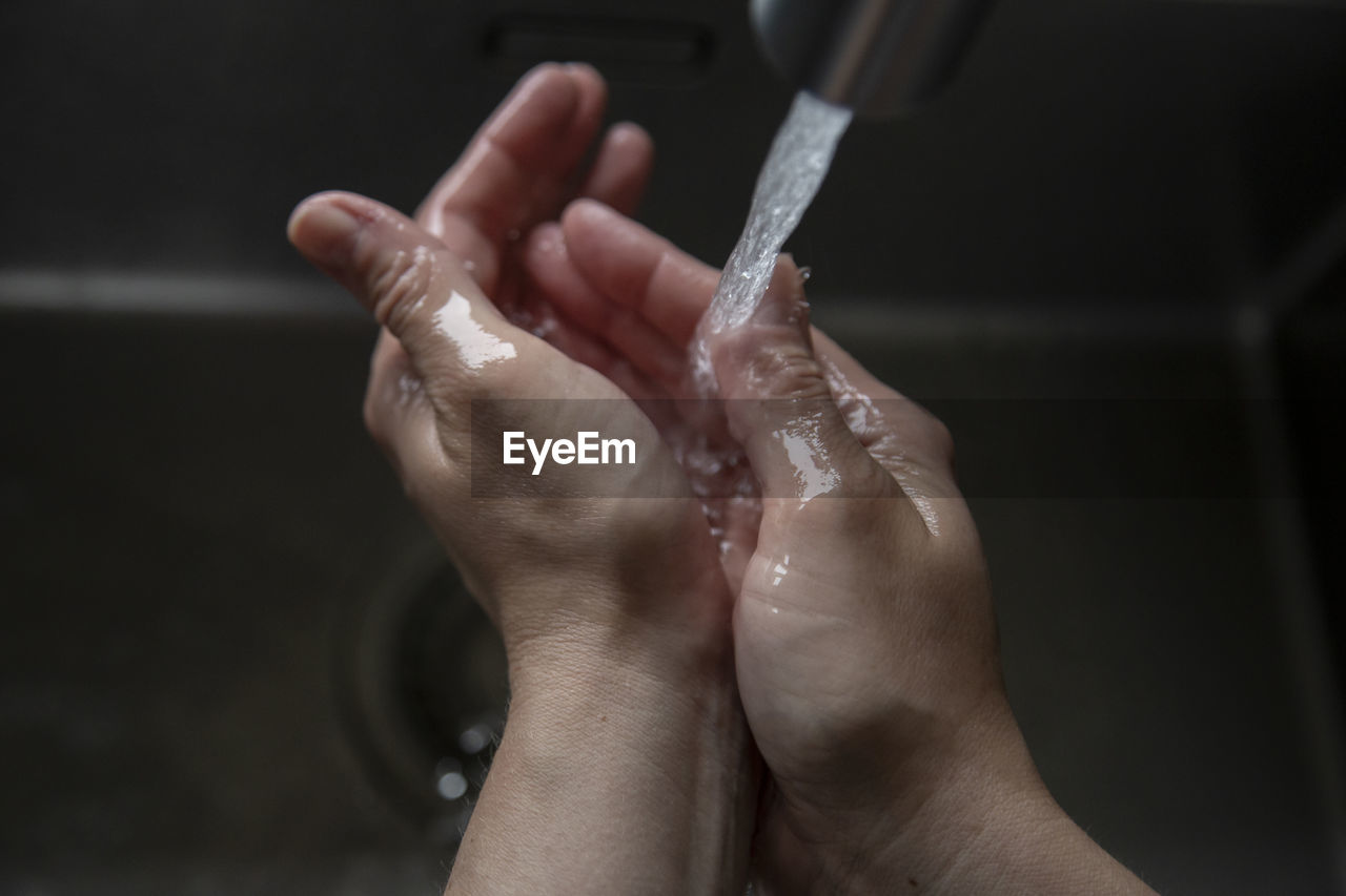 Close up of caucasian person washing their hands in the sink