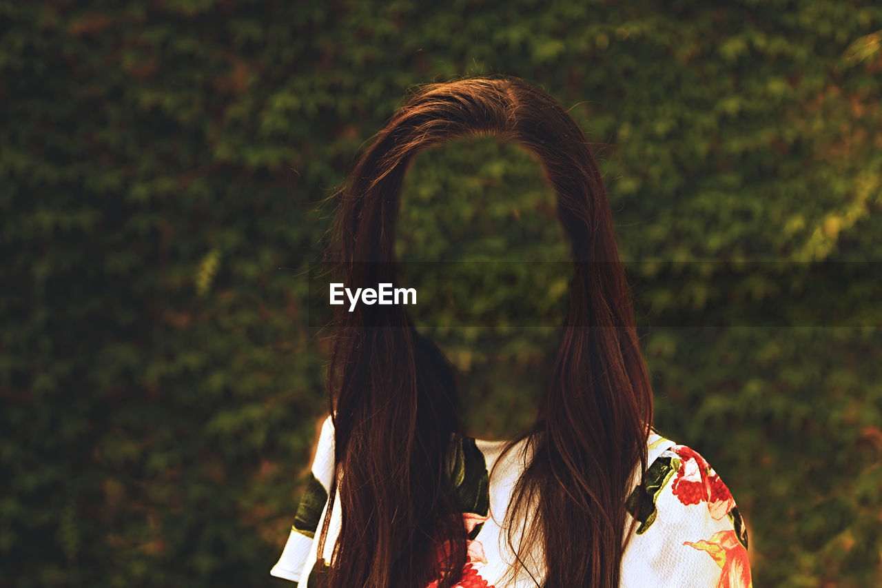 Digital composite image of faceless woman standing against plants