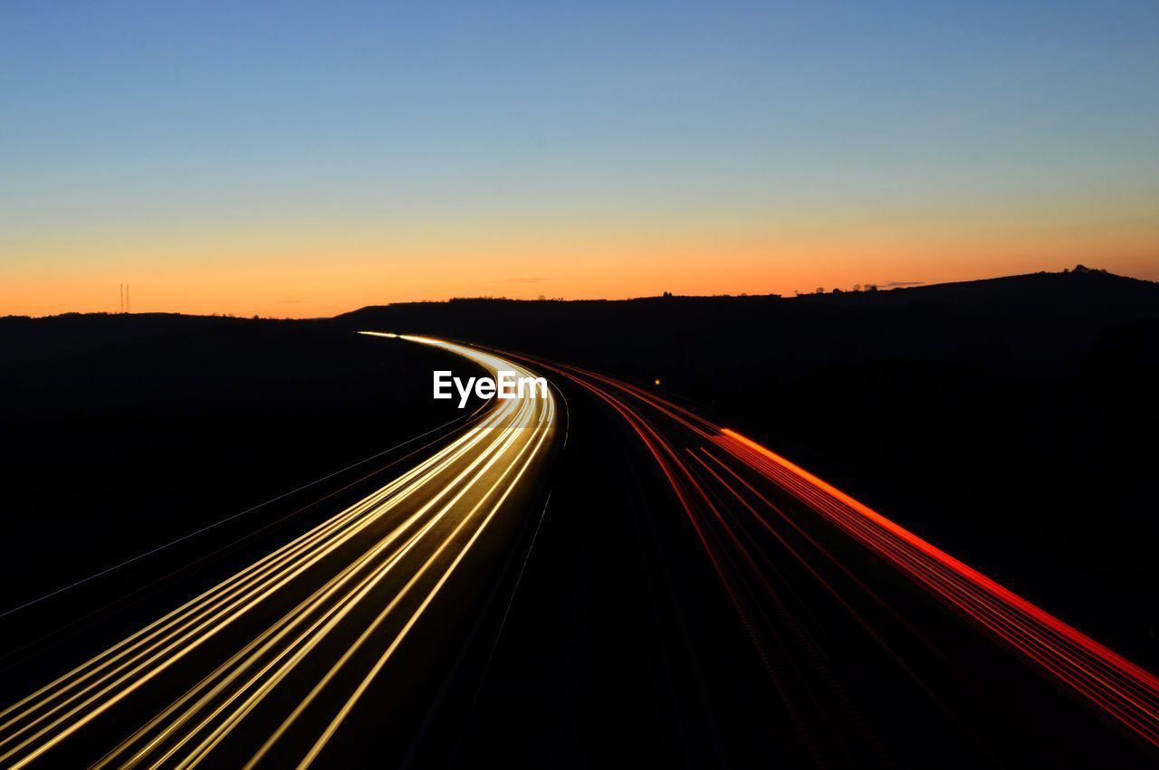 Light trails on highway against sky at night