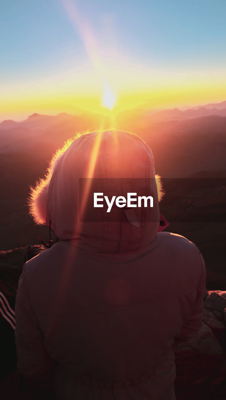 Rear view of woman against sky during sunset