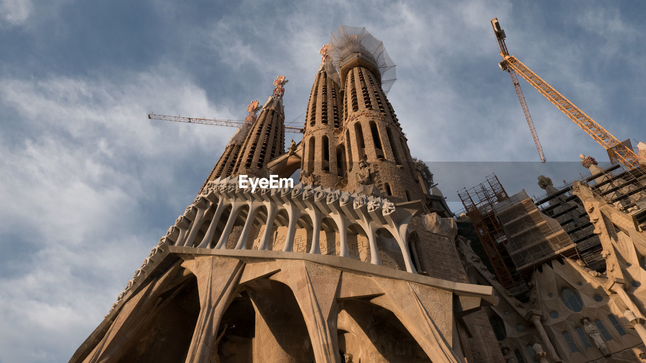 Low angle view of cranes at sagrada familia against sky