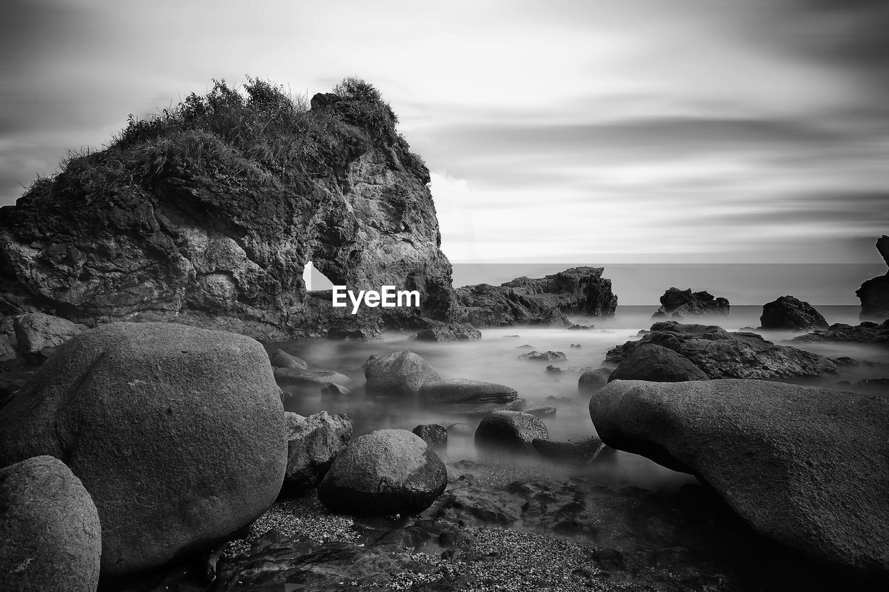 Scenic view of rocks on beach against sky