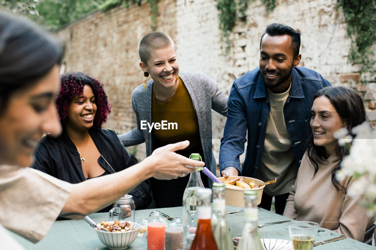 Happy friends spending leisure time with each other at garden party in back yard