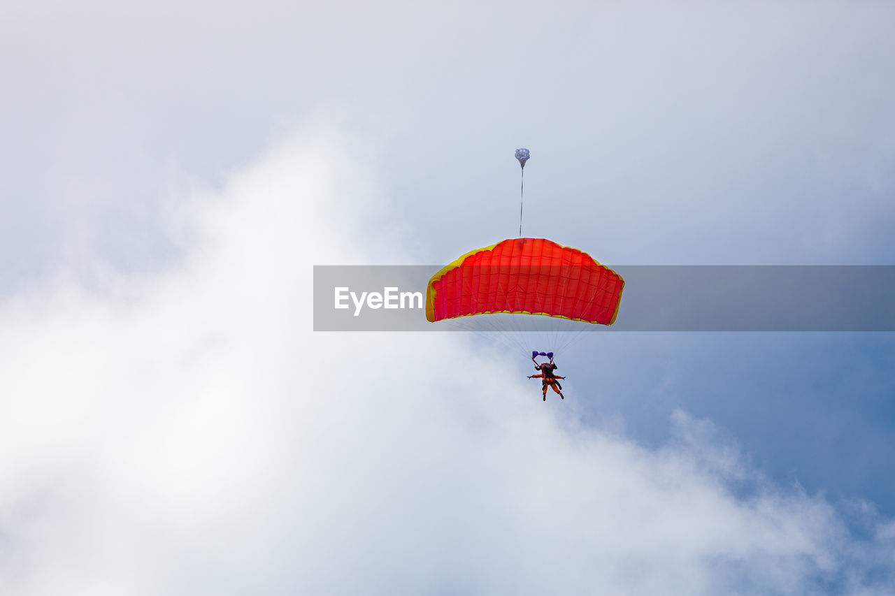 low angle view of man paragliding against sky