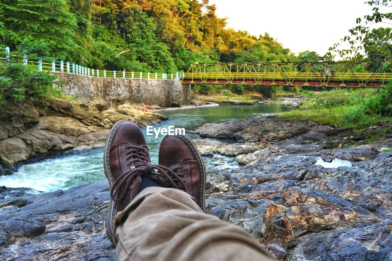 Low section of man sitting at waterfall