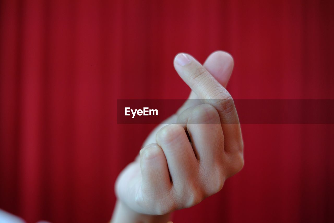 Close-up of hand gesturing against curtain