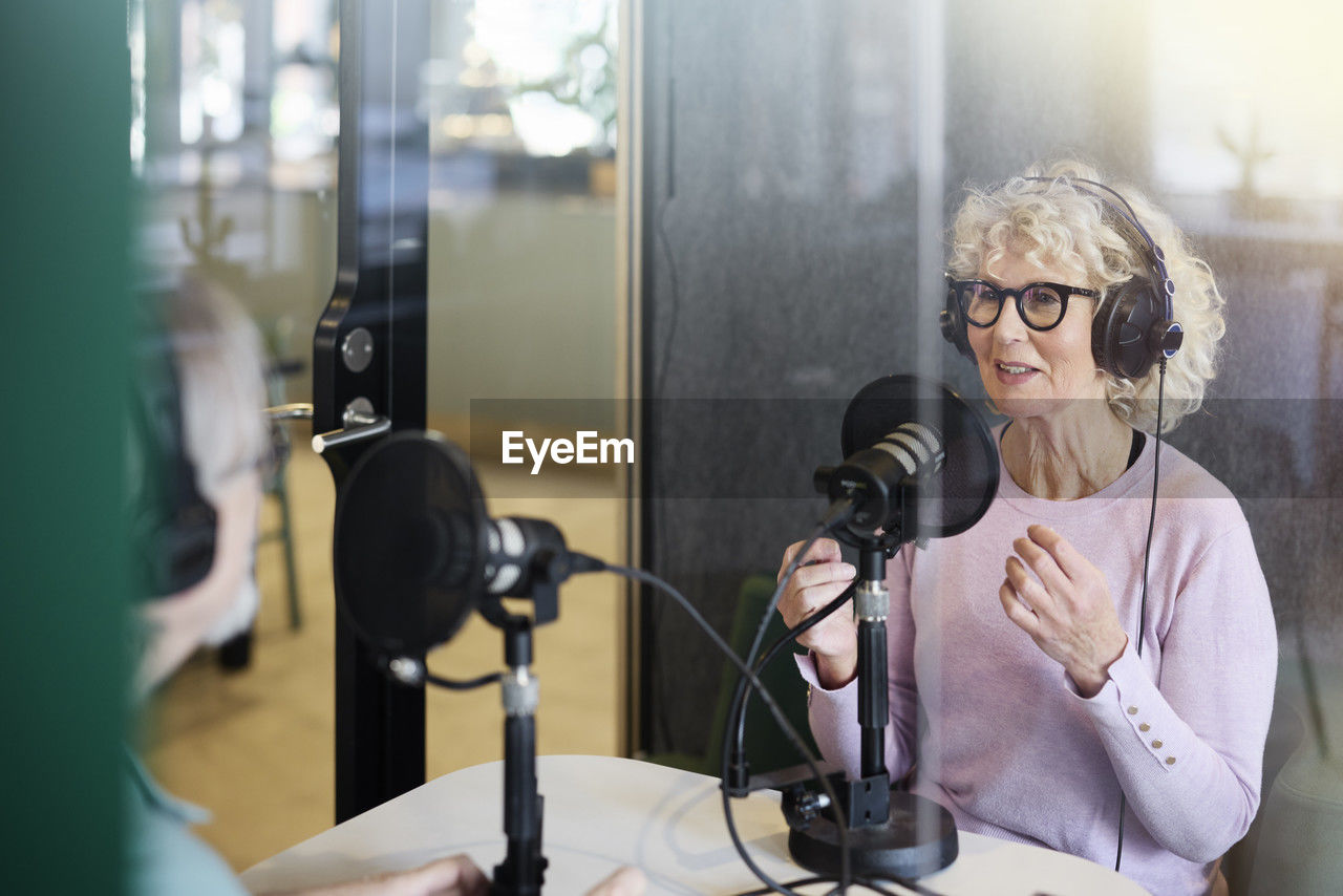 Mature woman sitting and hosting podcast or radio show or podcast