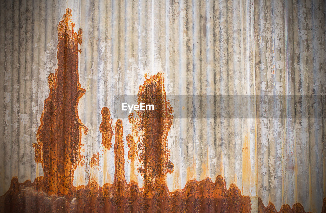Close-up of rusty metal fence against wall