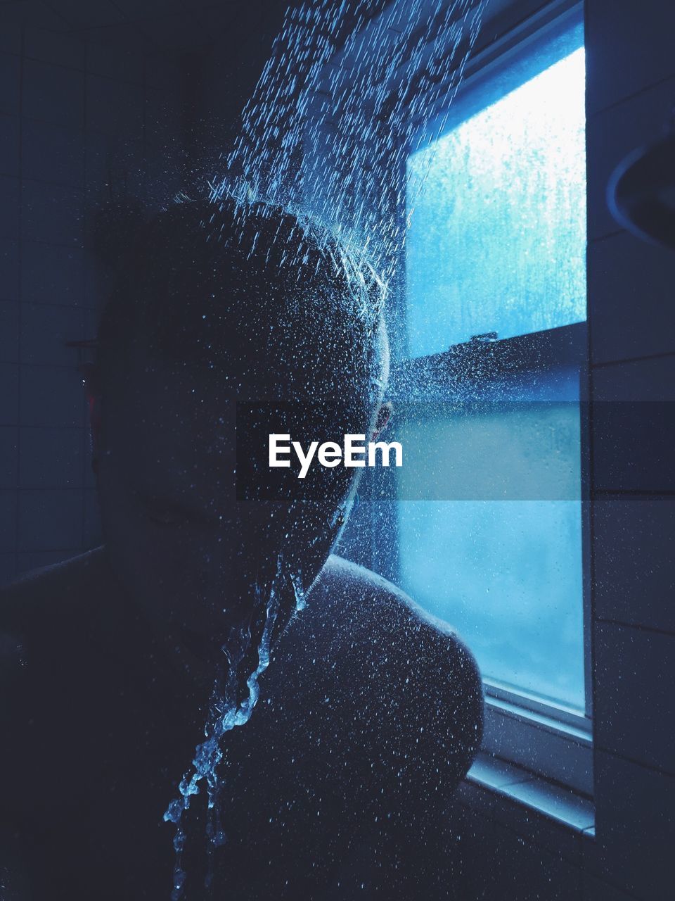 Shirtless man taking shower in bathroom