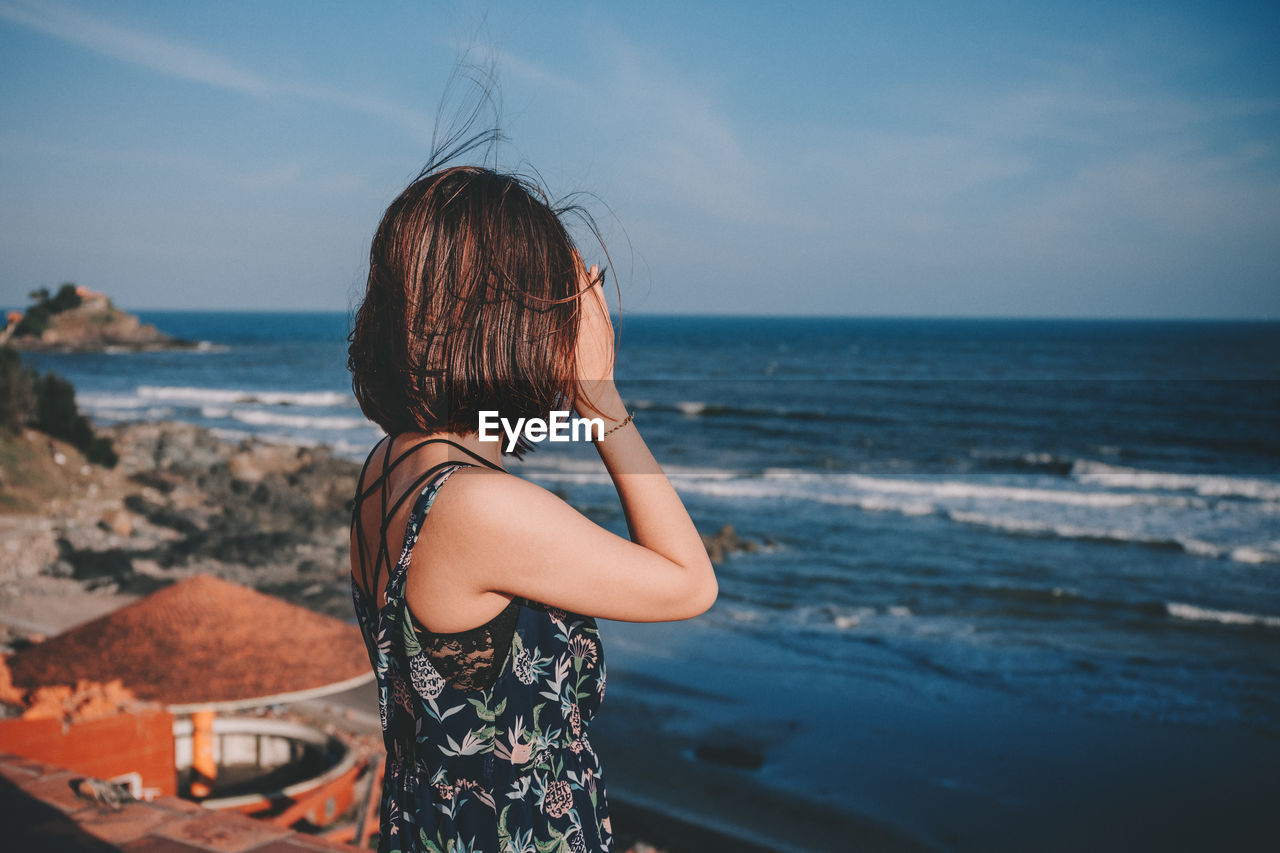 Side view of woman looking at sea against sky