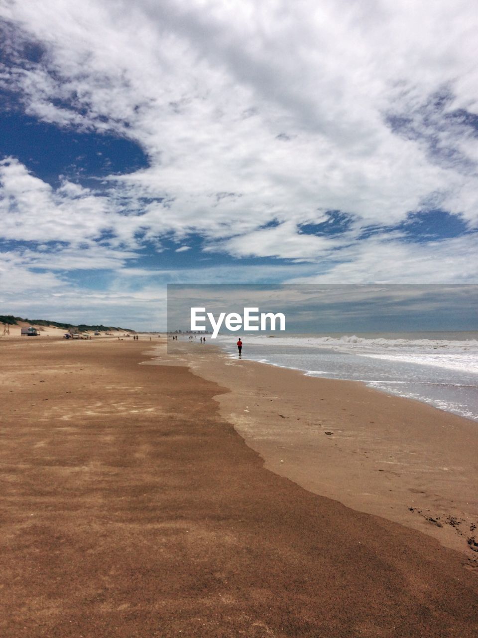 View of calm beach against cloudy sky