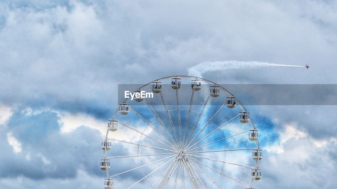 Low angle view of ferris wheel against cloudy sky