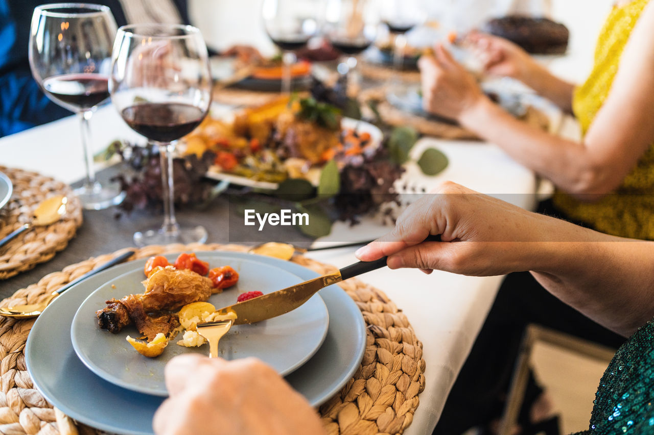 From above of crop unrecognizable people enjoying tasty dish while sitting at table during christmas holiday