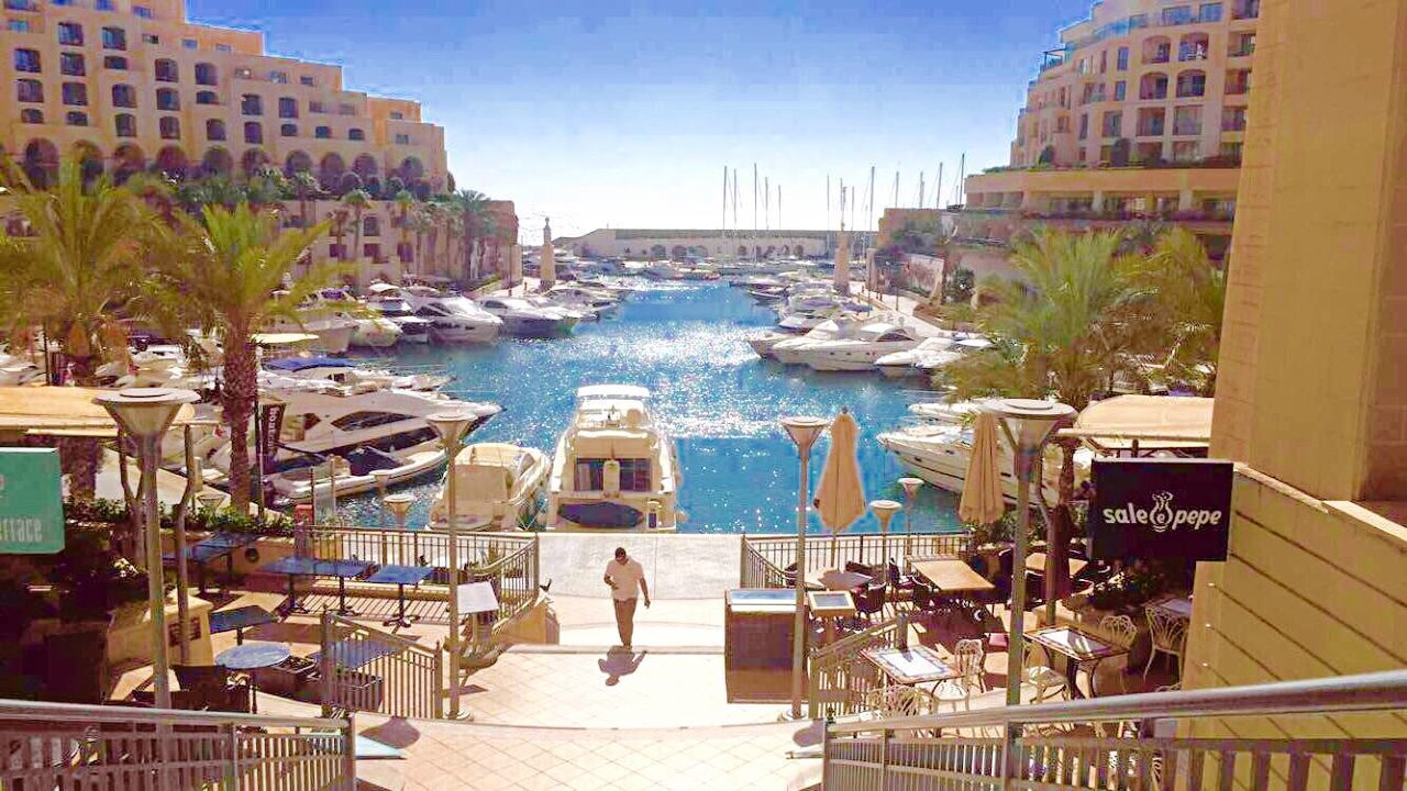 BOATS IN RIVER WITH BUILDINGS IN BACKGROUND