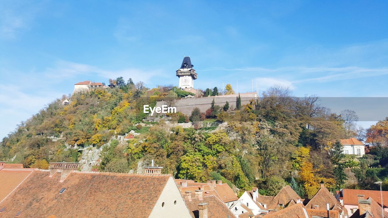 Low angle view of buildings on hill against blue sky