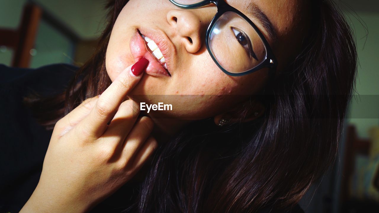 Close-up portrait of young woman with finger on lips