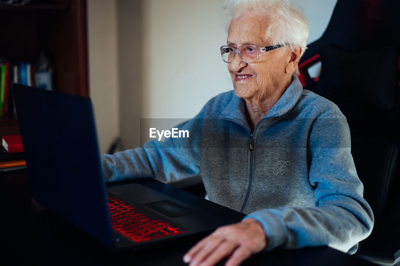 Smiling senior woman using laptop while sitting at home