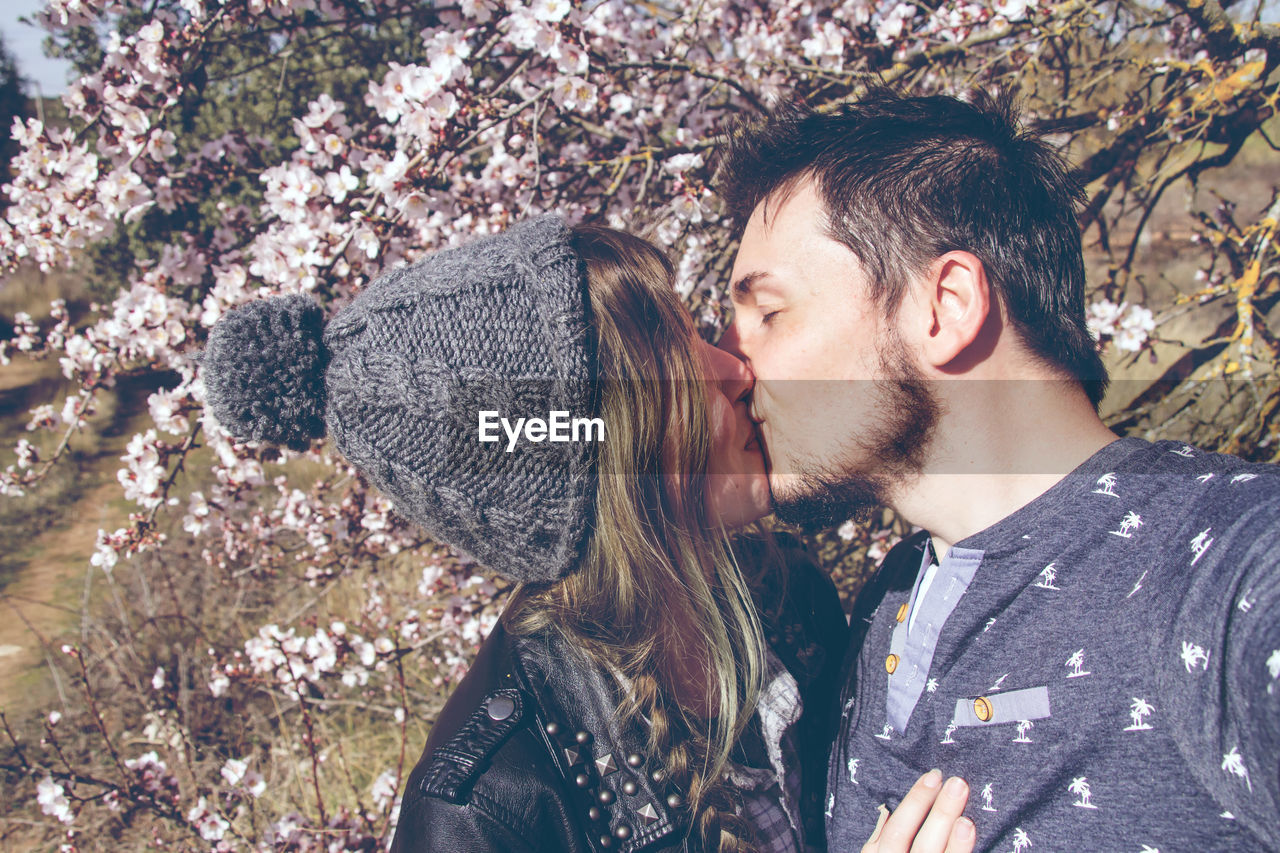 Young couple kissing against trees