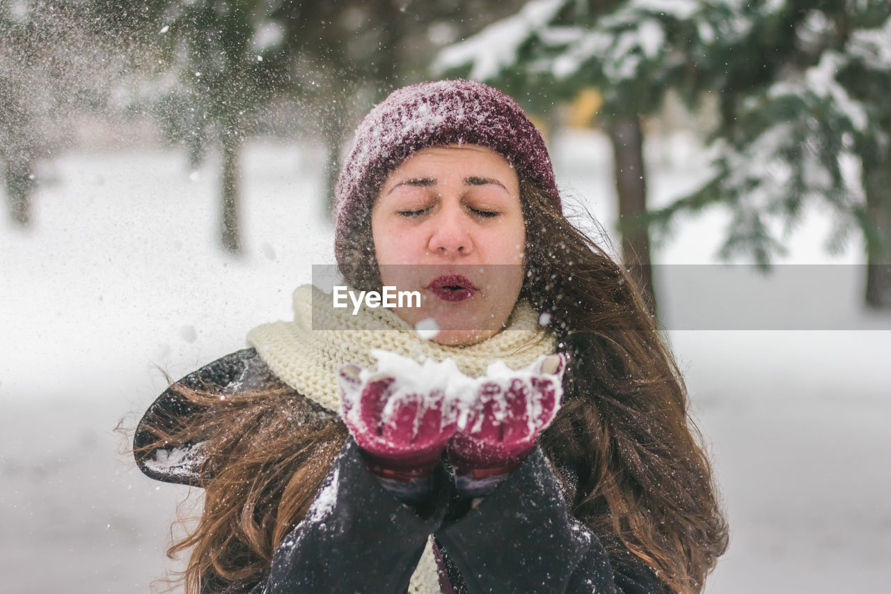 Close-up of woman blowing snow