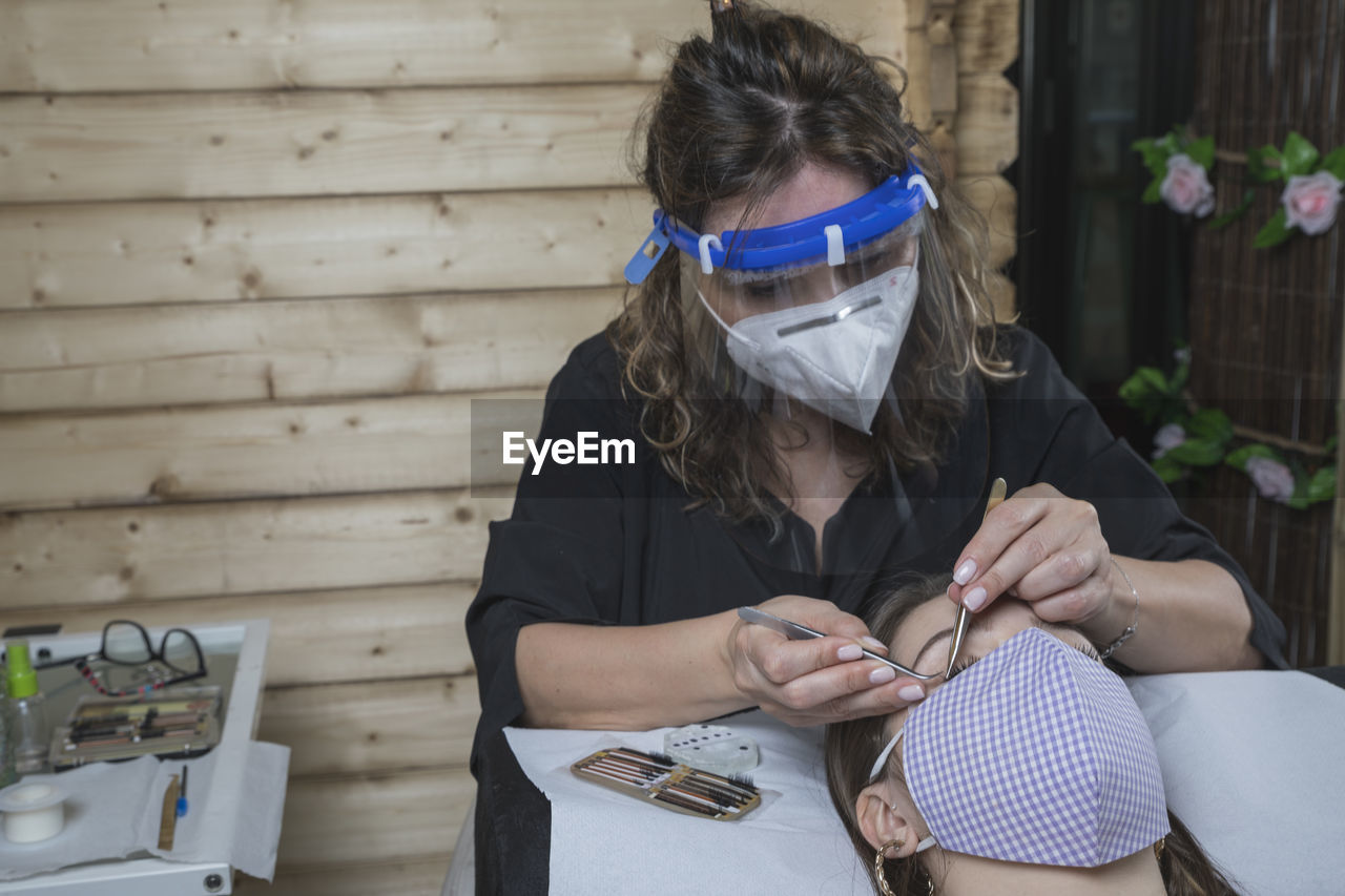 Beautician working with mask and protective screen for the virus covid