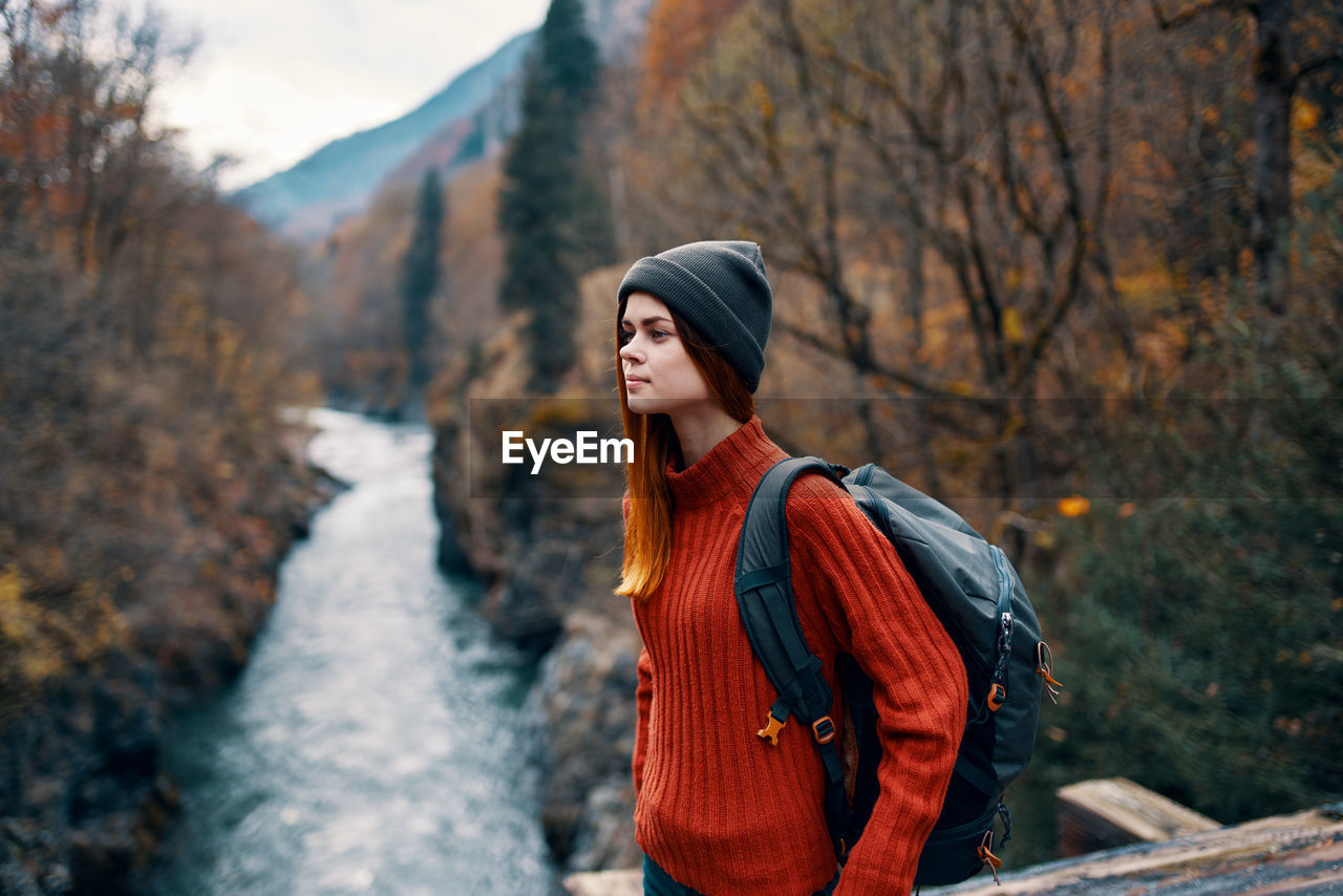 YOUNG WOMAN LOOKING AWAY WHILE STANDING ON LAND