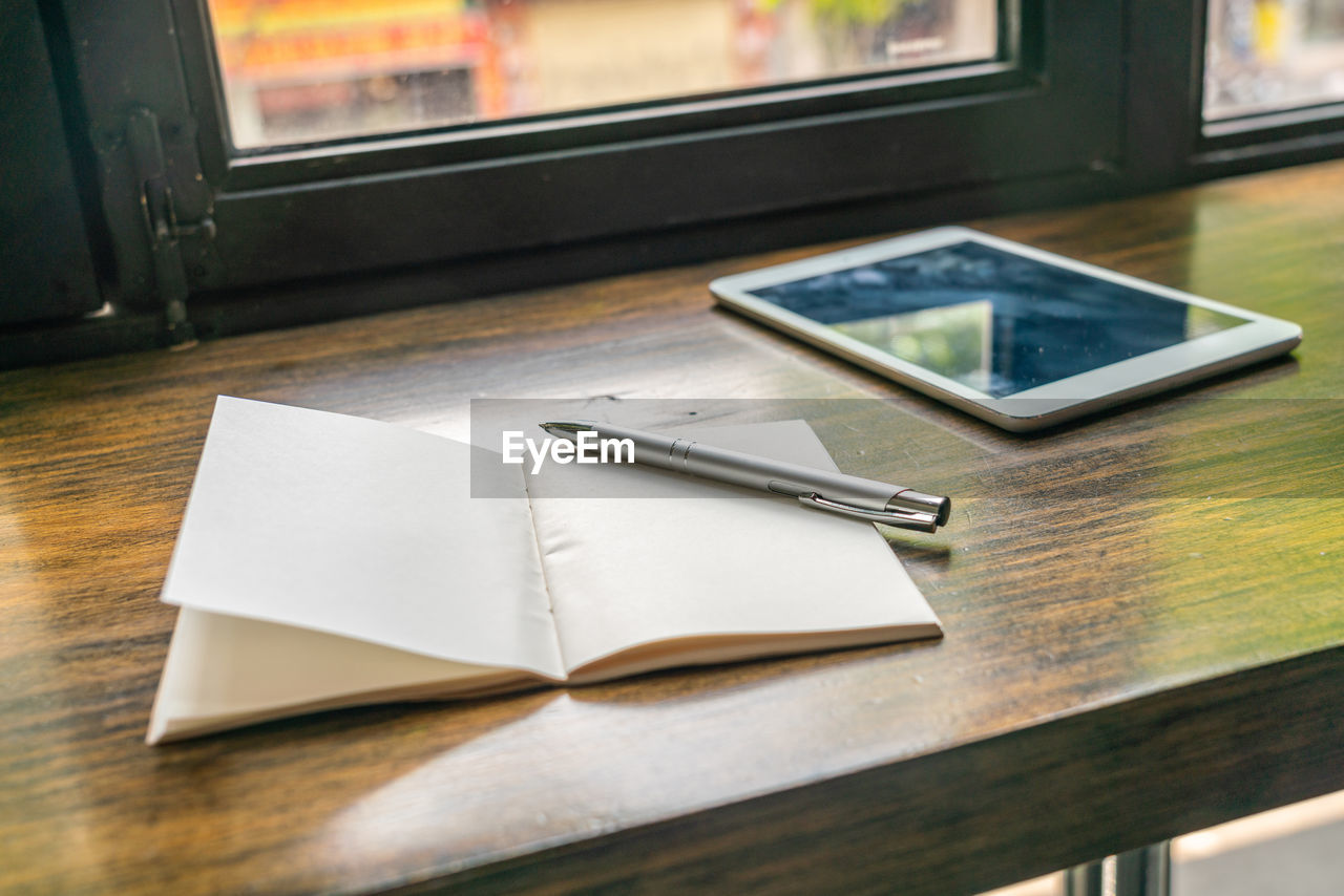 HIGH ANGLE VIEW OF MOBILE PHONE AND BOOK ON TABLE