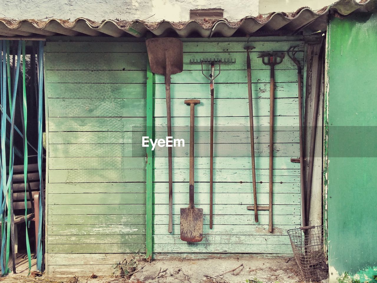 Gardening equipment hanging on green wooden wall