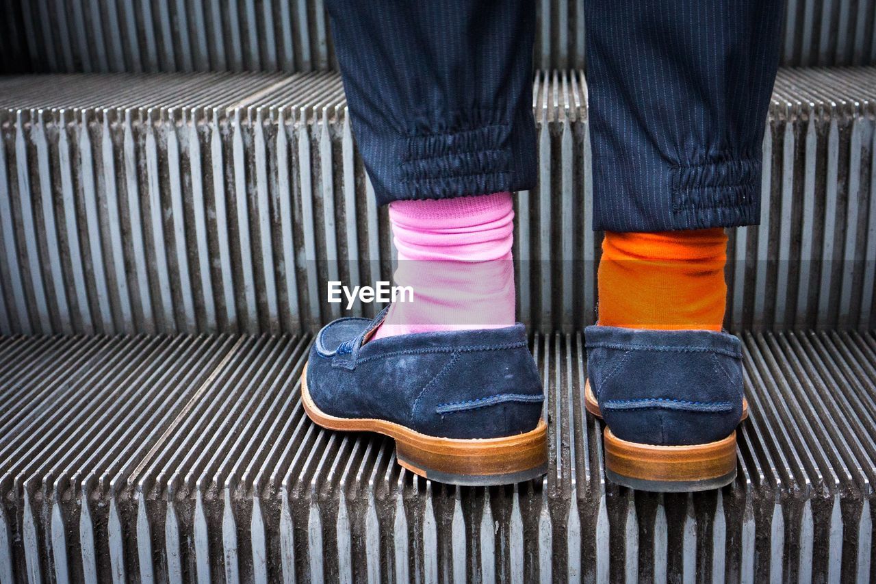 Midsection of a person wearing two different socks on escalator