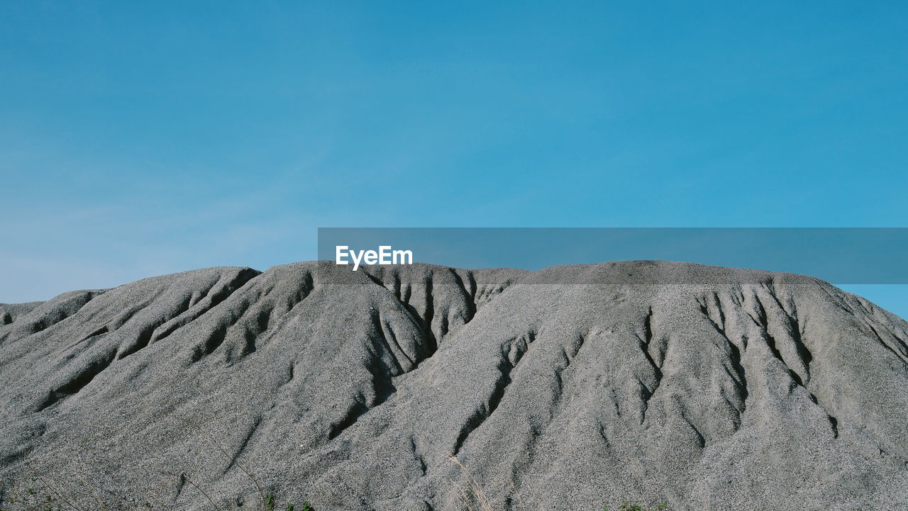 Scenic view of arid landscape against blue sky