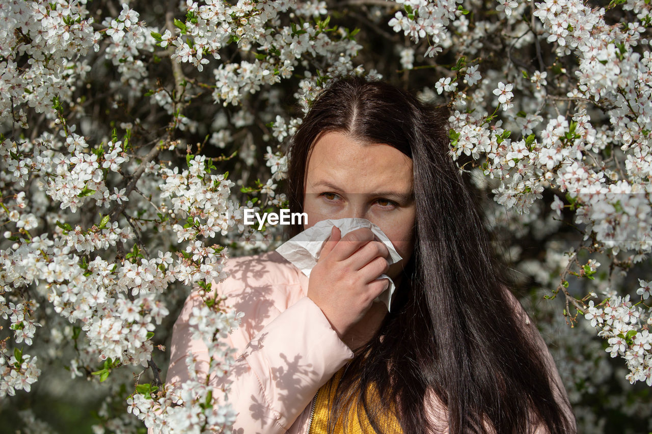 young woman drinking water against plants