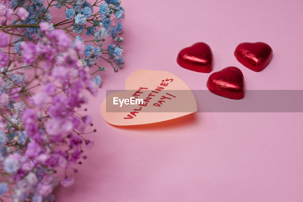 Heart-shaped candies and love message on pink background