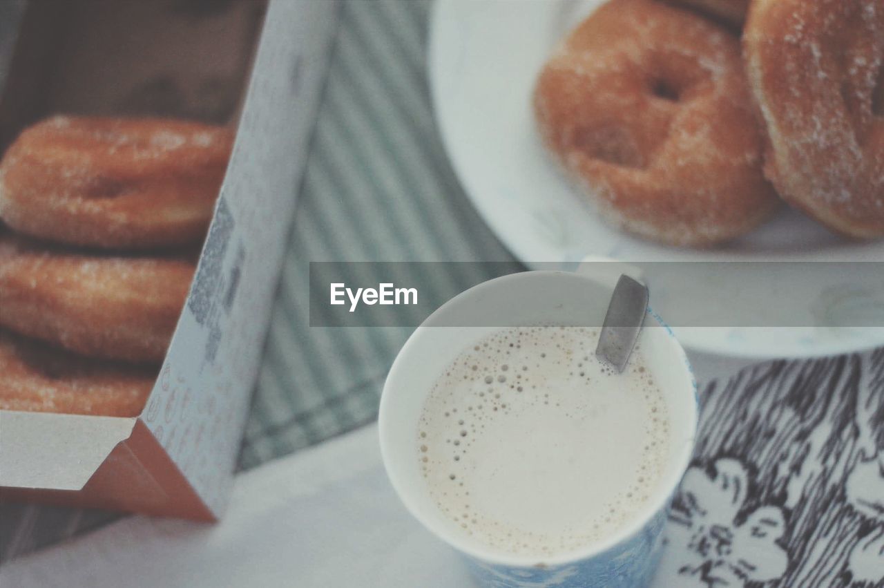 High angle view of coffee by donuts on table