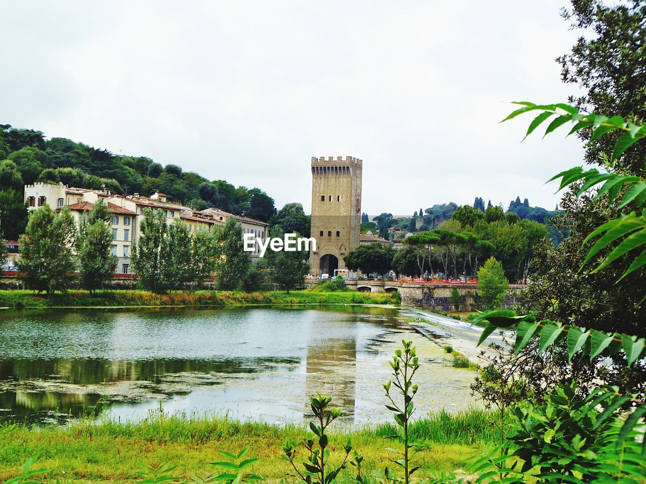 Lake in front of historic building against cloudy sky