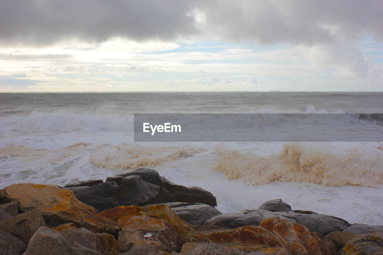 ROCKS ON SHORE AGAINST SKY