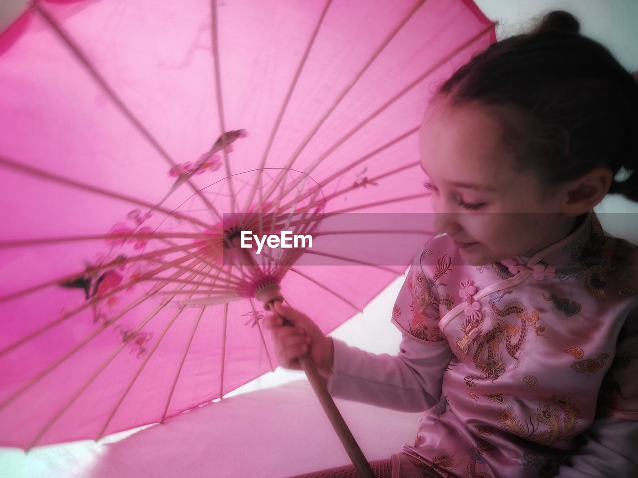 GIRL LOOKING AWAY WHILE PINK UMBRELLA