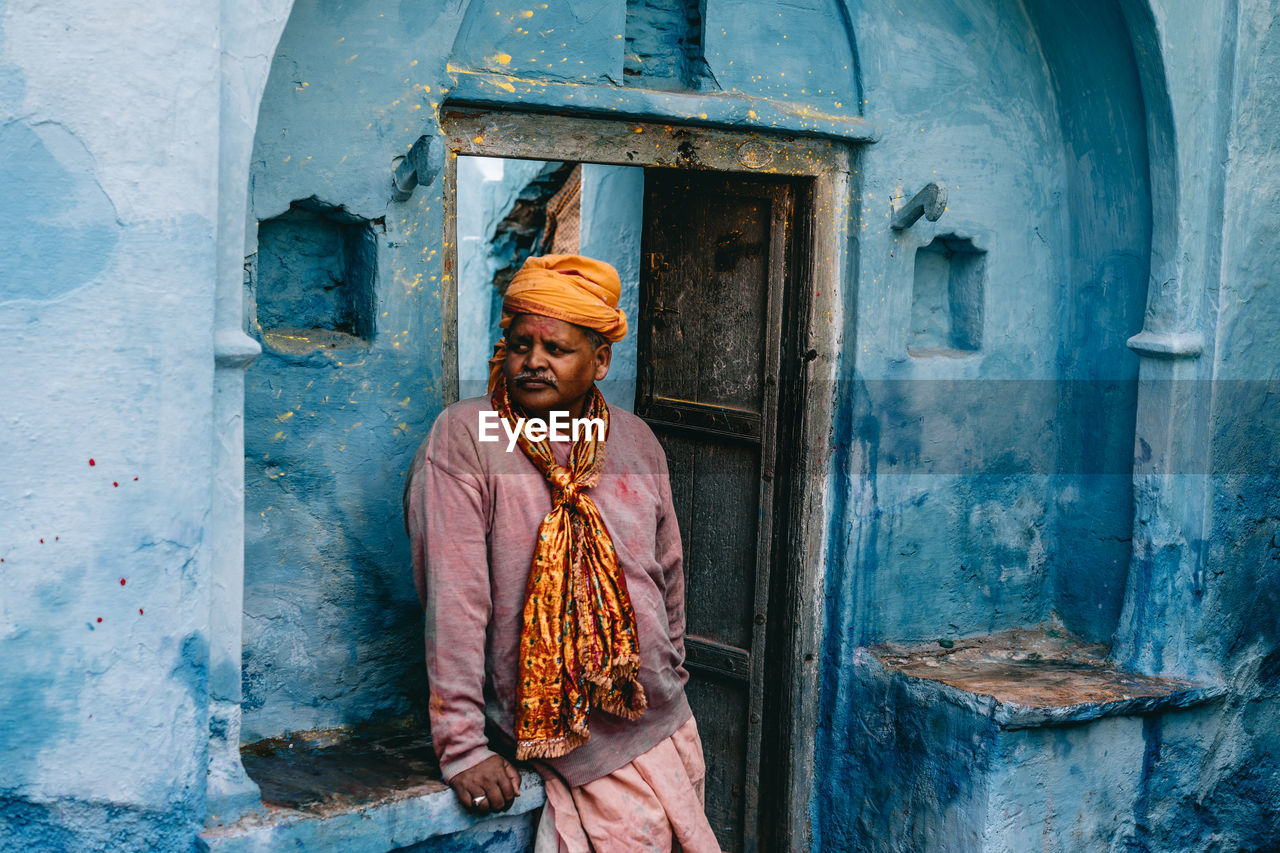 PORTRAIT OF SMILING STANDING AGAINST DOOR