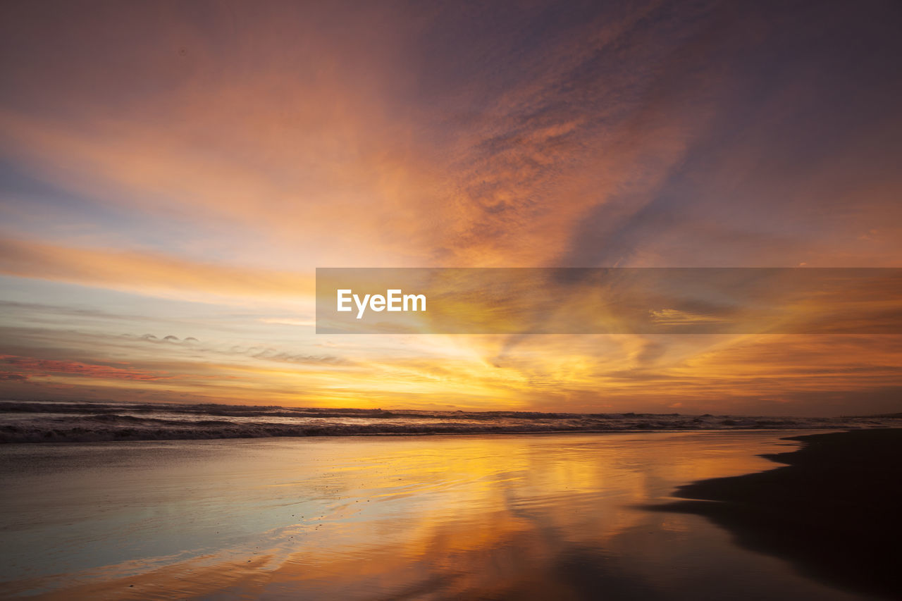 SCENIC VIEW OF BEACH AGAINST ORANGE SKY