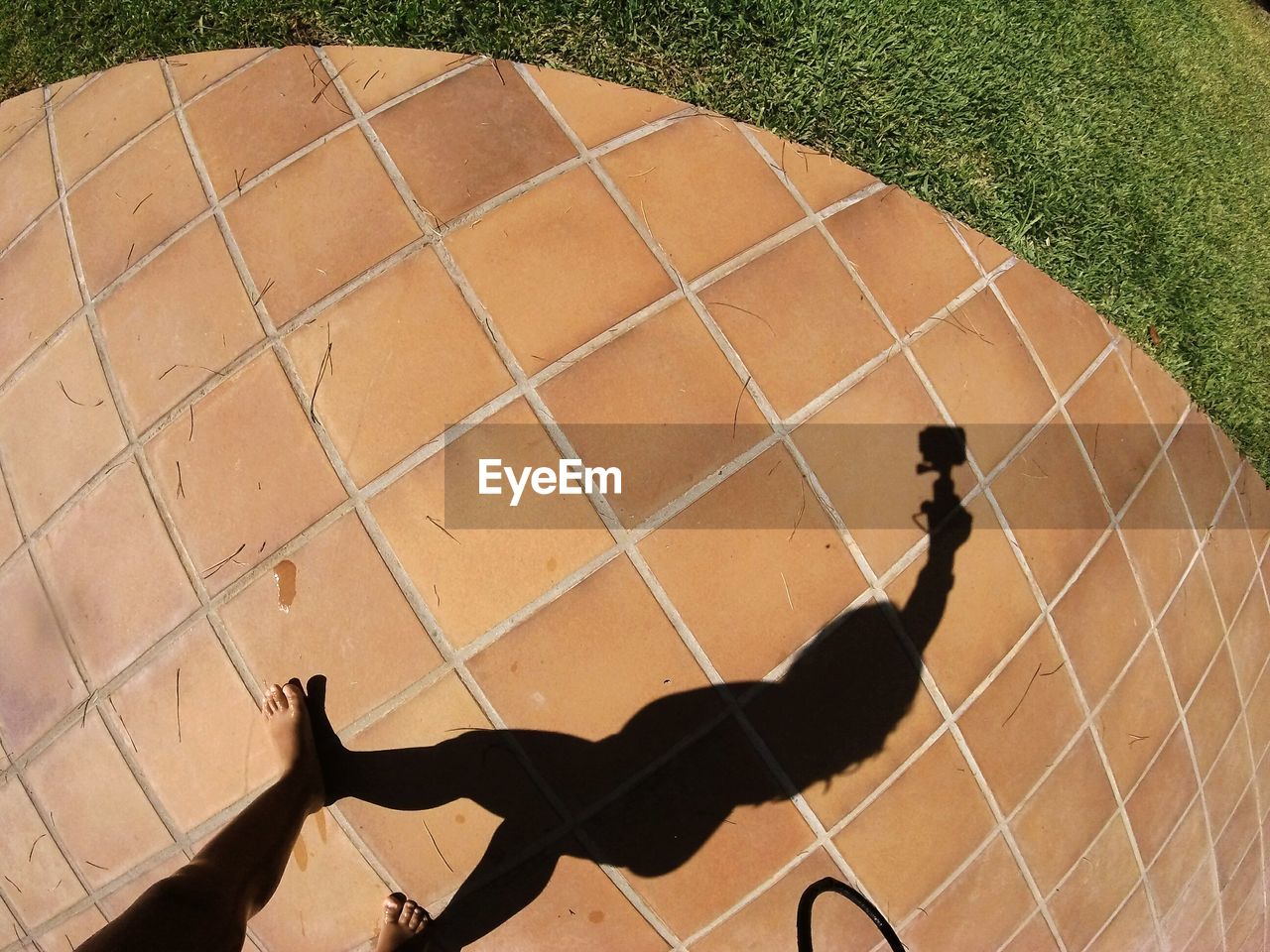 Low section of woman on footpath with shadow