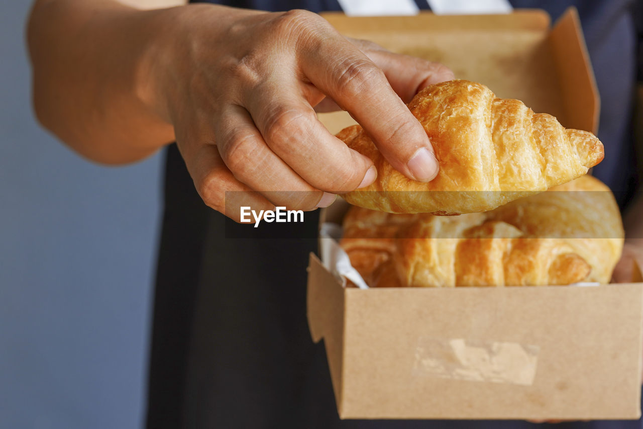 Girl's hand picks croissant from box, concept croissant online, order online. take away