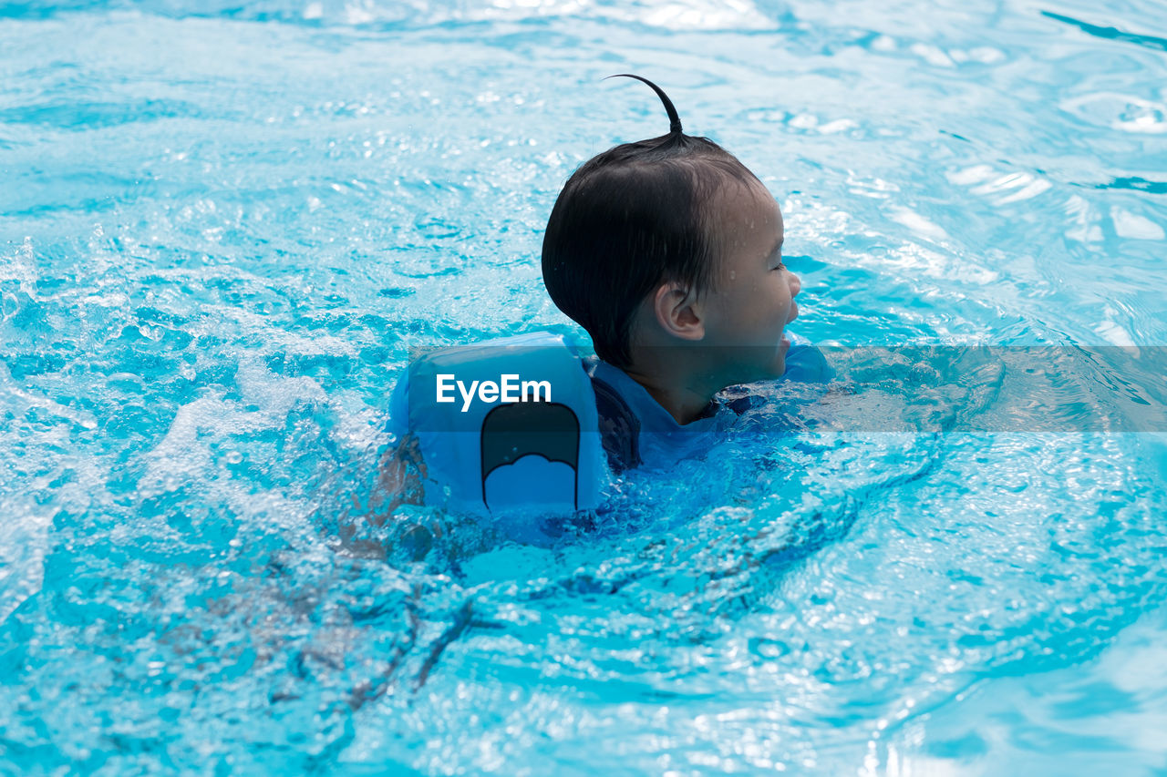 Boy wearing water wings while swimming in pool